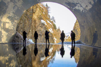 Menschen blicken auf einer Höhle in die Berglandschaft