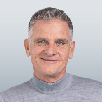 Kursleister Peter Stark trägt einen grauen Pullover und lächelt