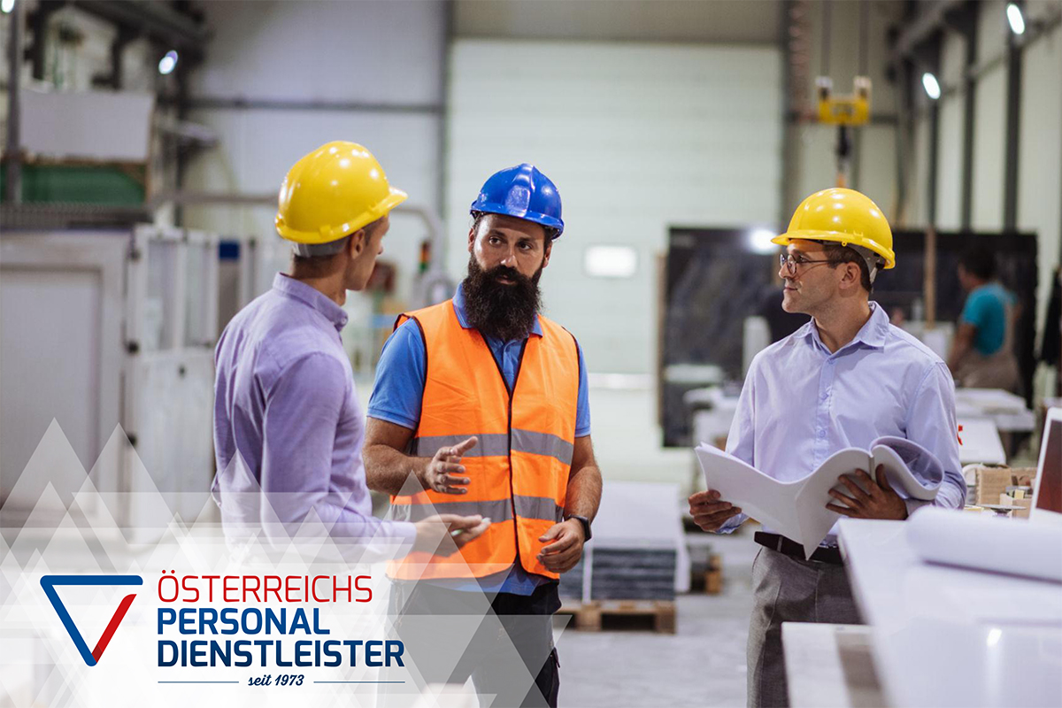 Drei M&auml;nner mit Schutzhelmen und Sicherheitsausr&uuml;stung stehen in einer Fabrik und diskutieren. Zwei halten Dokumente in der Hand. Auf dem Logo steht: "&Ouml;STERREICHS PERSONAL DIENSTLEISTER seit 1987".